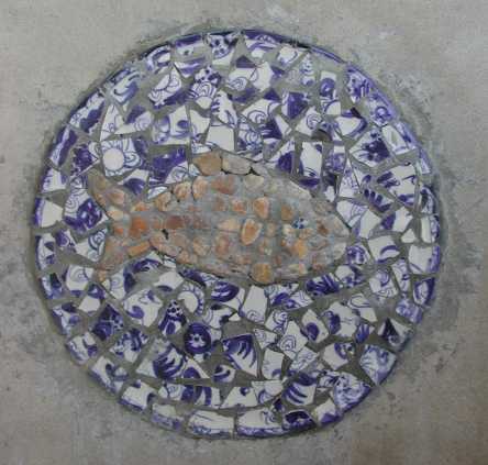 A detail of ceramic plate fragments and river rocks forming a pertinent symbol